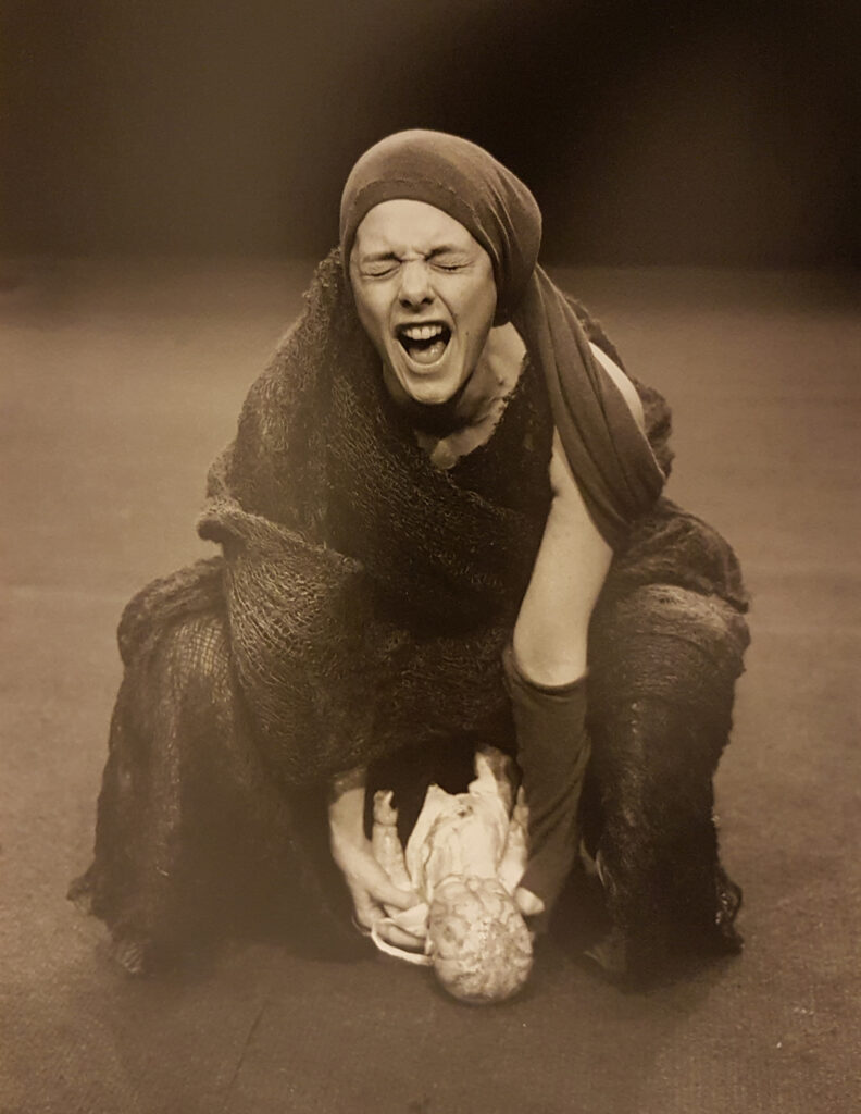 Woman dressed in rags, giving birth to a baby (a doll). Scene from Macbeth - witches.