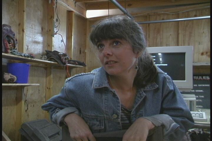 Woman turned away from a keyboard, leaning over the back of a chaire.