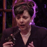 Woman holding revolver and staring at it.