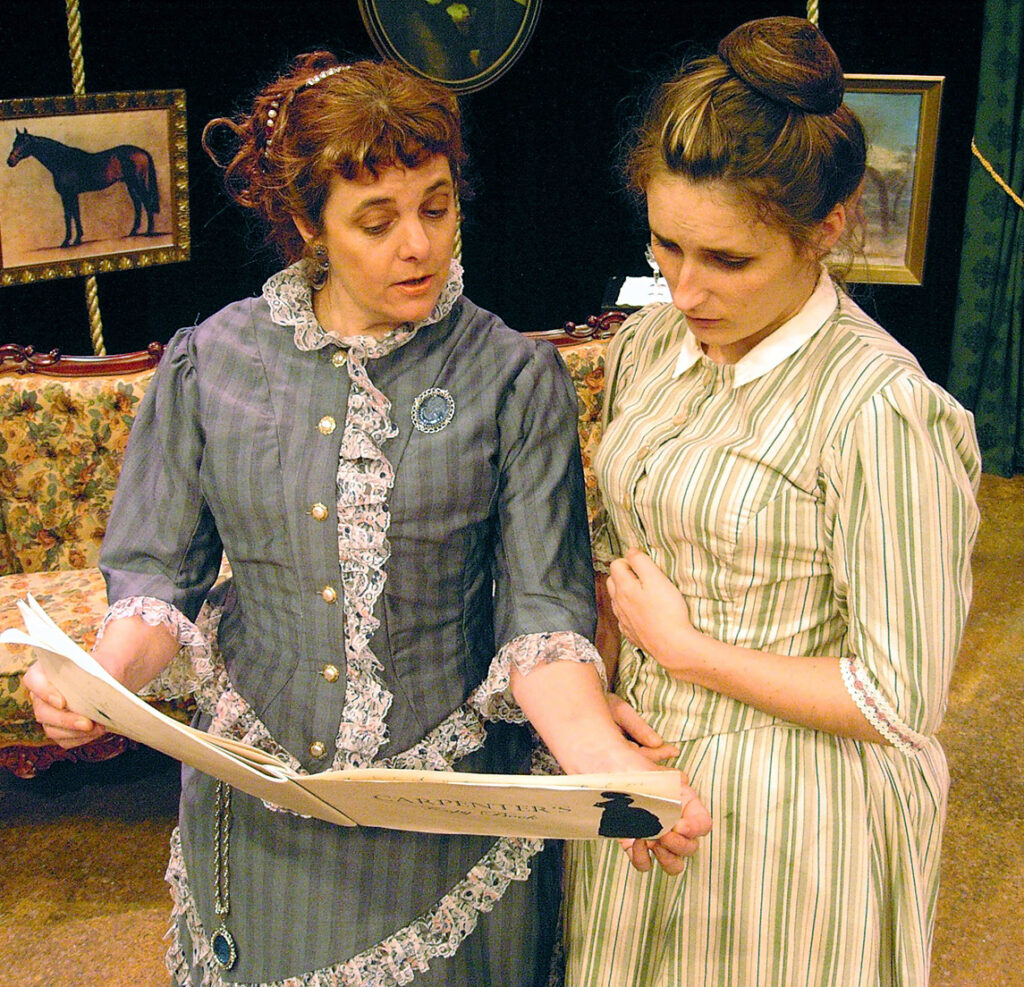 Two women in Victorian dress looking at a copybook.